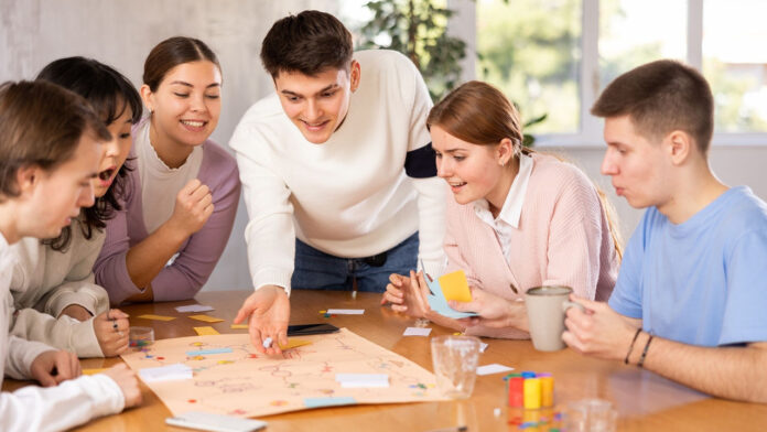 Young guys and girls playing board game together